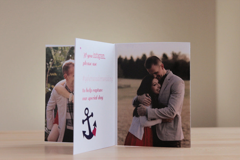 Centerpiece sitting on a wooden table with a neutral wall in the background. The panels show engagement pictures of the couple hugging and instructions for social media hashtags along with navy and pink icon of an anchor and heart.