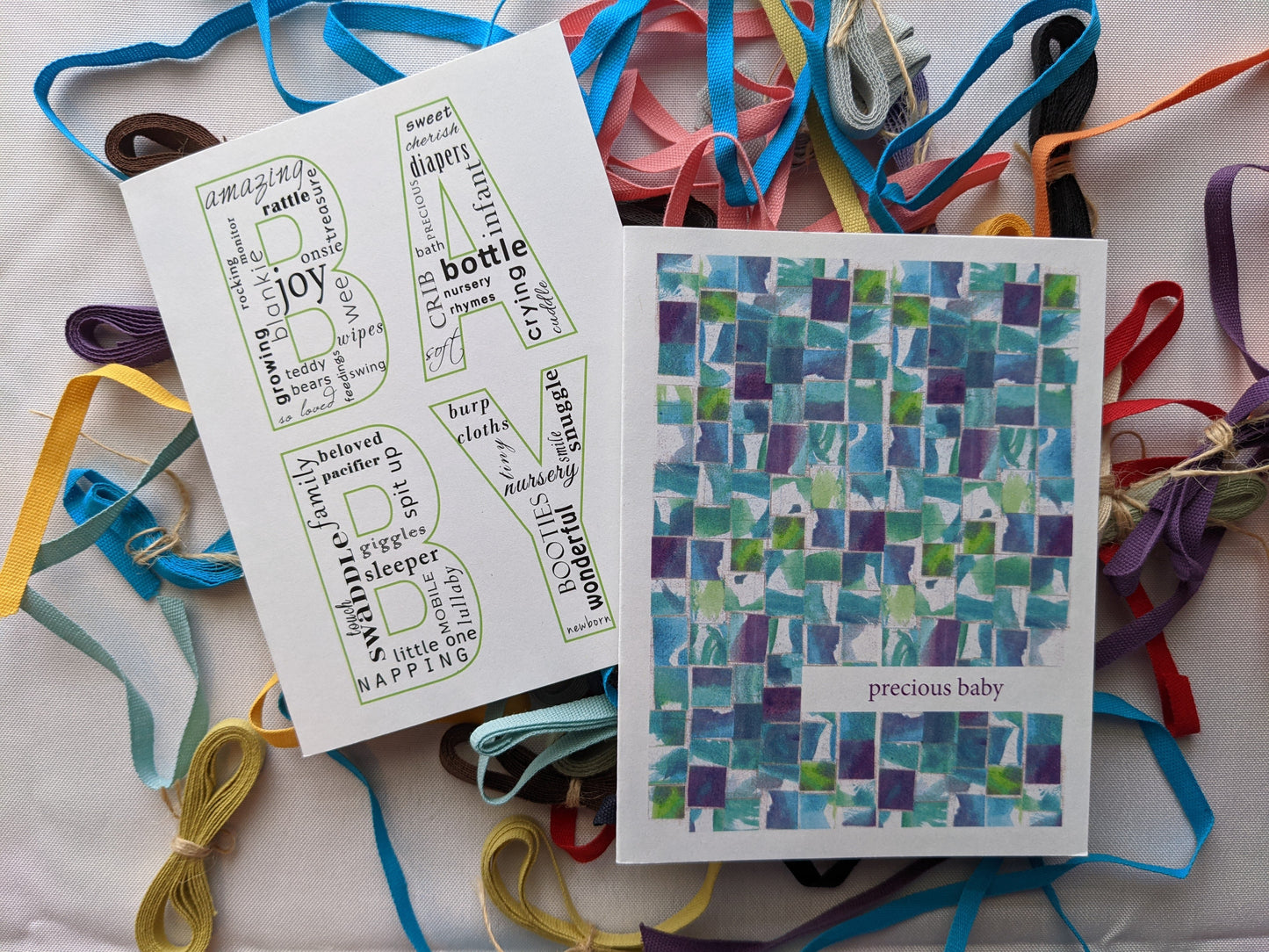Two greeting cards overlapping on a white background with colorful cotton ribbons.