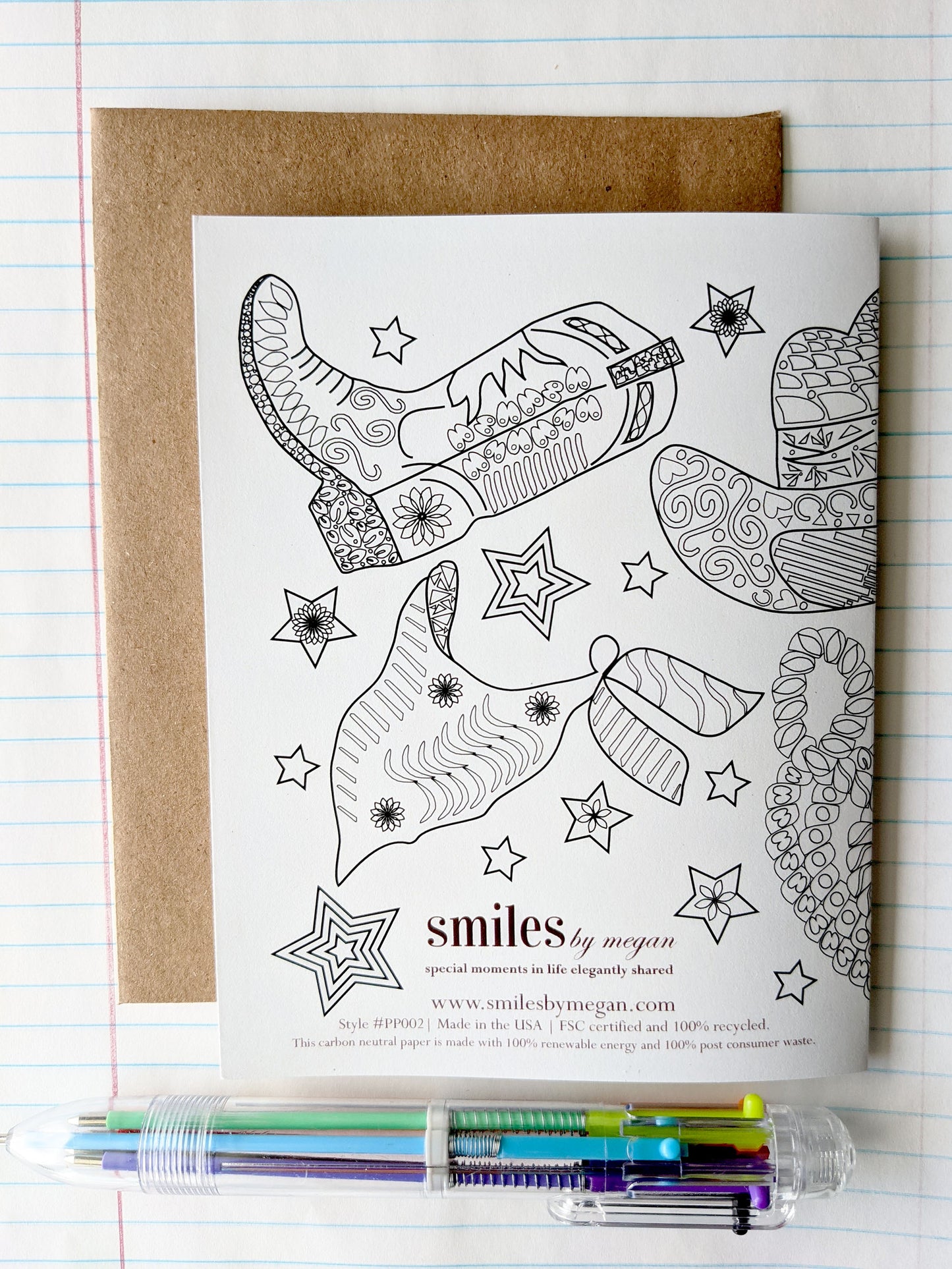 Back side of greeting card on top of a kraft envelope against lined notebook paper.
