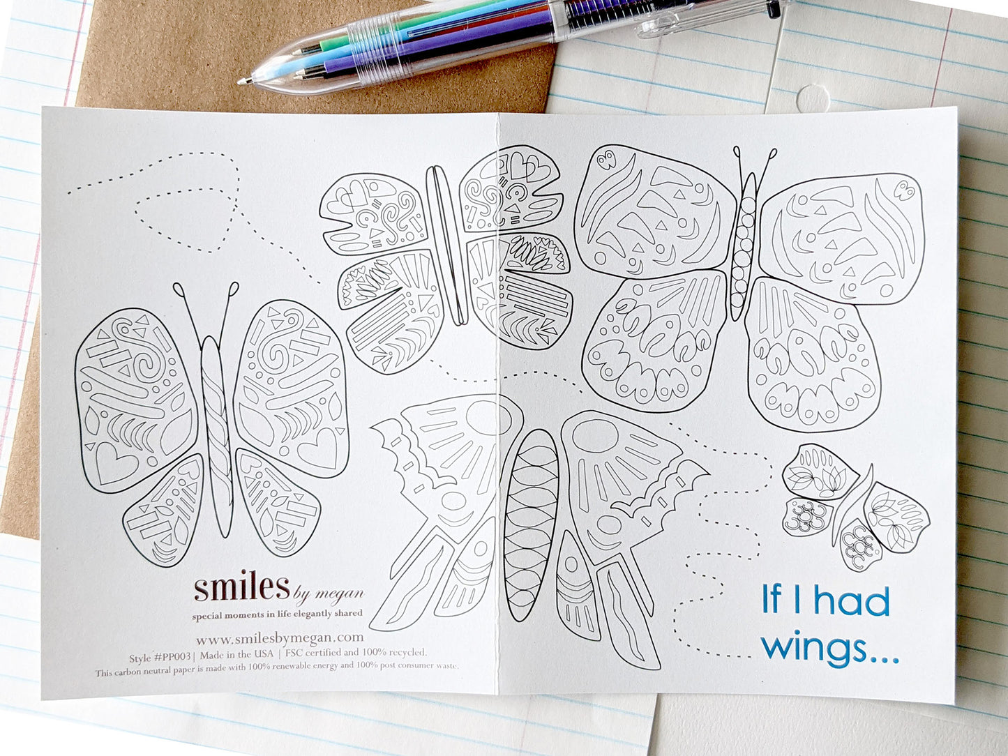 Open greeting card showing the image spanning both the back and the front with a kraft envelope, lined notebook paper and a multi-colored pen.