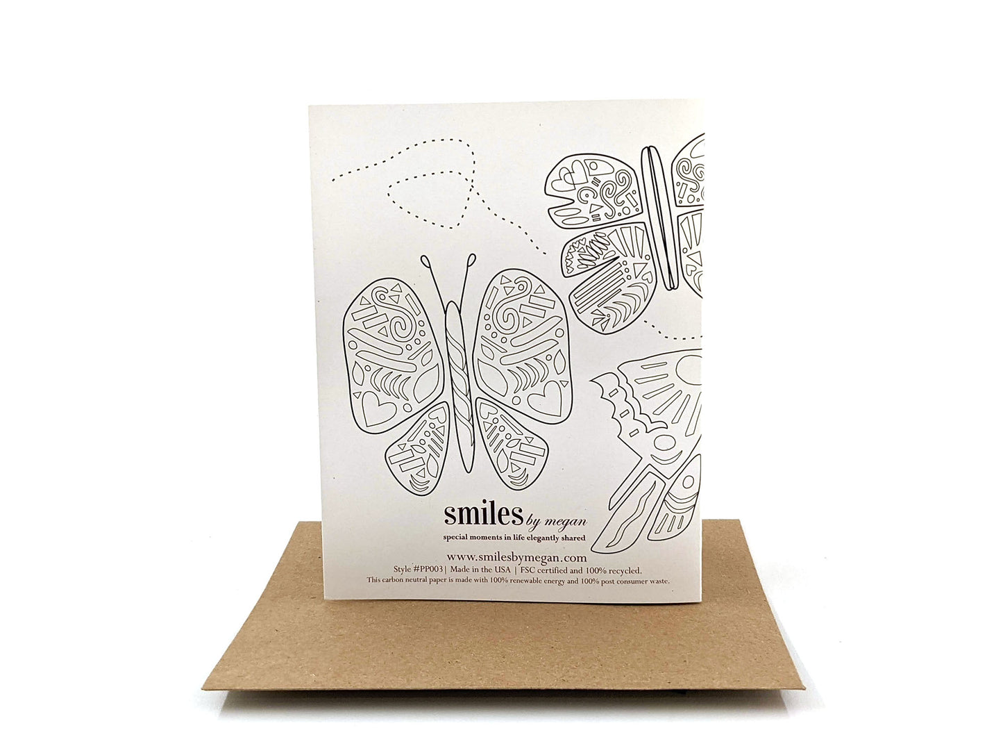 Back side of greeting card standing upright on top of a kraft envelope against a white background.