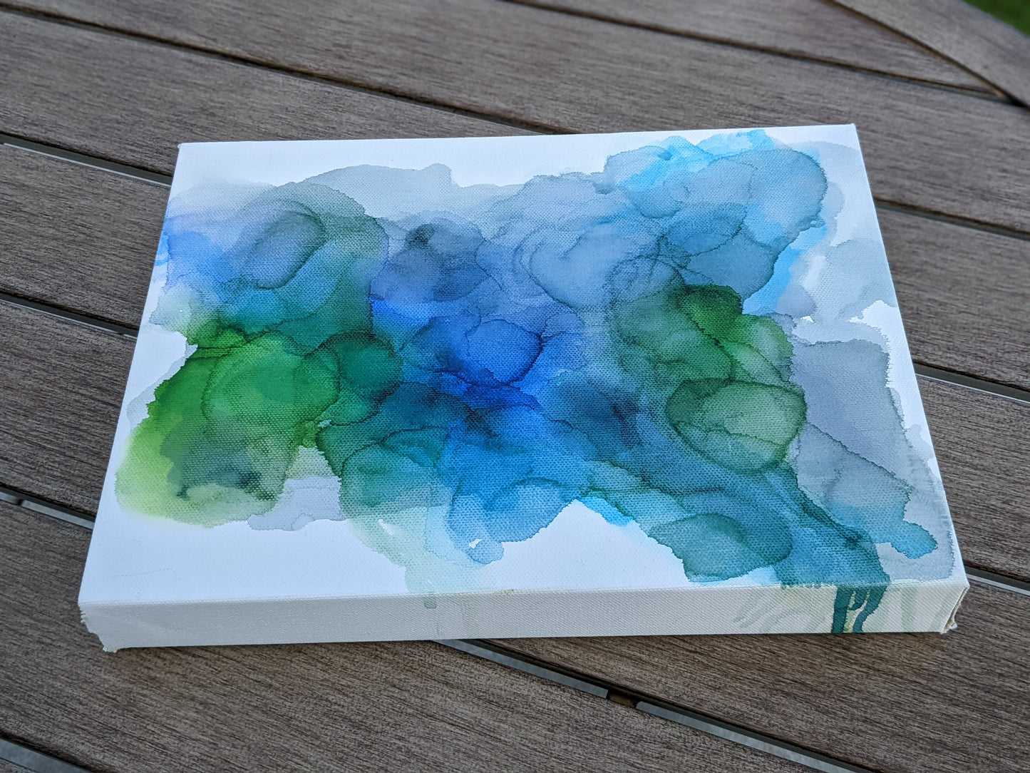 Photo angled from above of the canvas laying on a slat patio table.