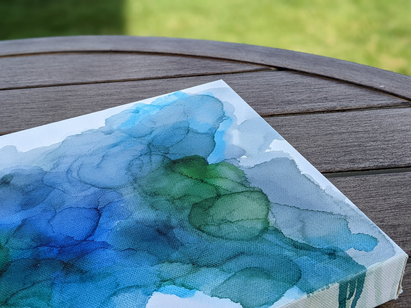 Photo angled from above of the canvas laying on a slat patio table.