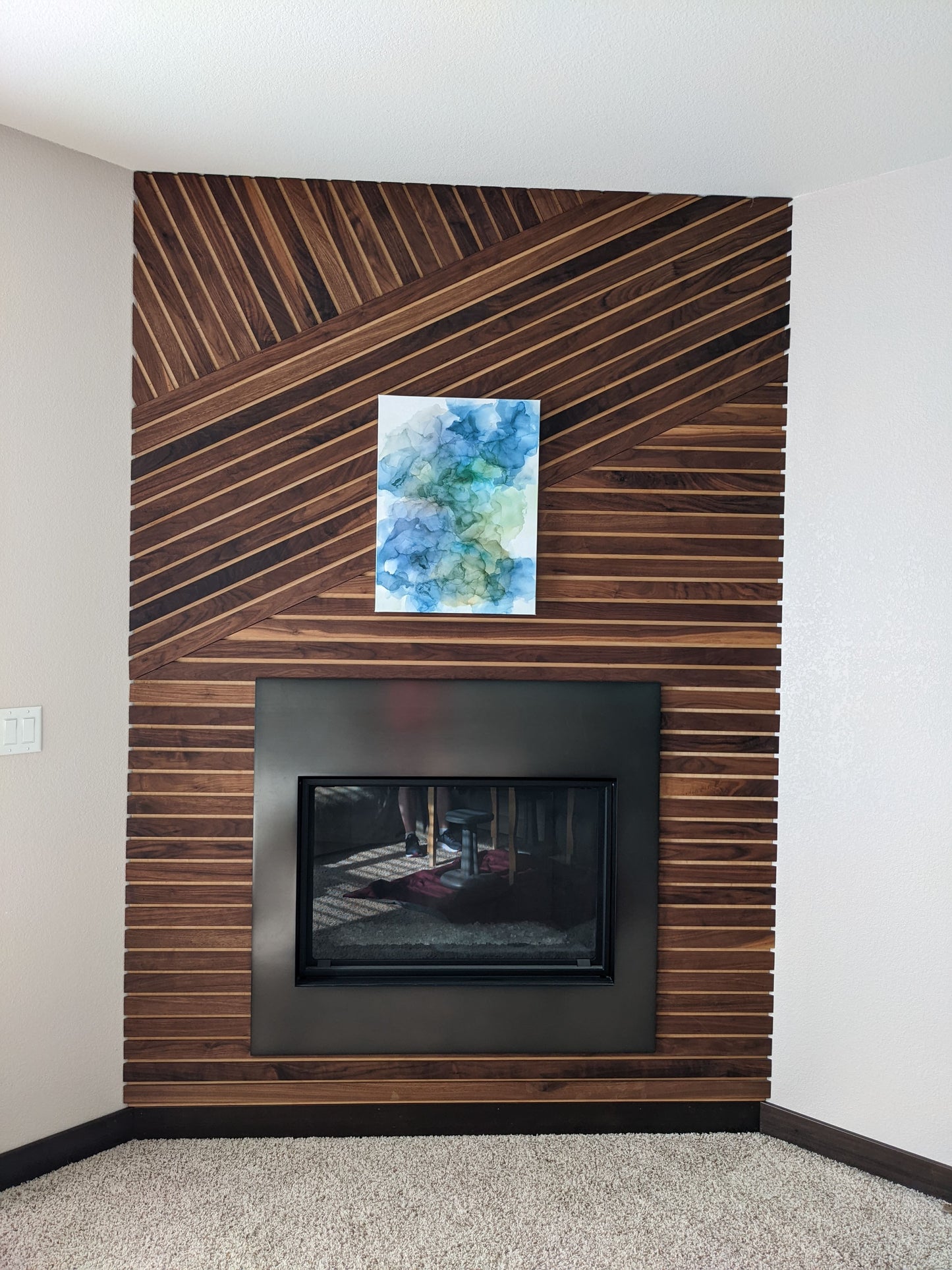 Canvas shown above a fireplace against a wood slat wall.