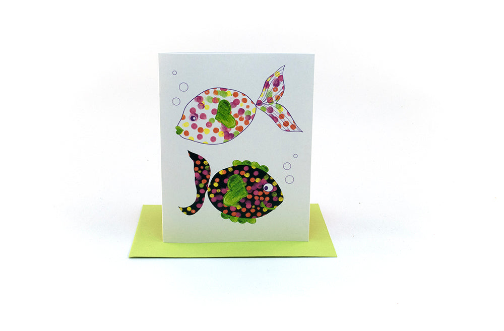 Greeting card standing upright on top of a colorful envelope against a white background.
