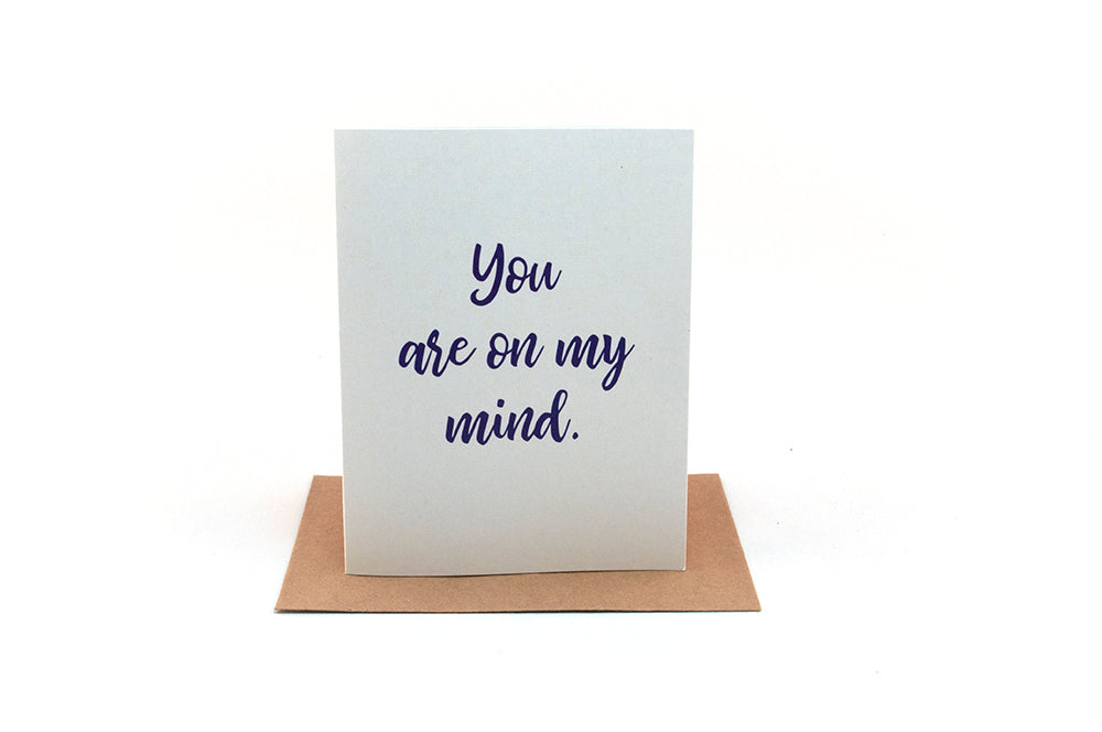 Greeting card standing upright on top of a colorful envelope against a white background.