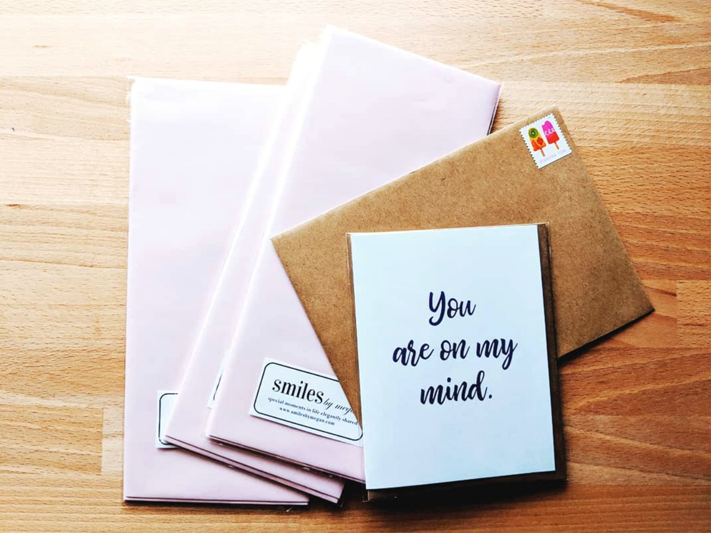 Greeting card laying on a stack of envelopes on a wooden table.