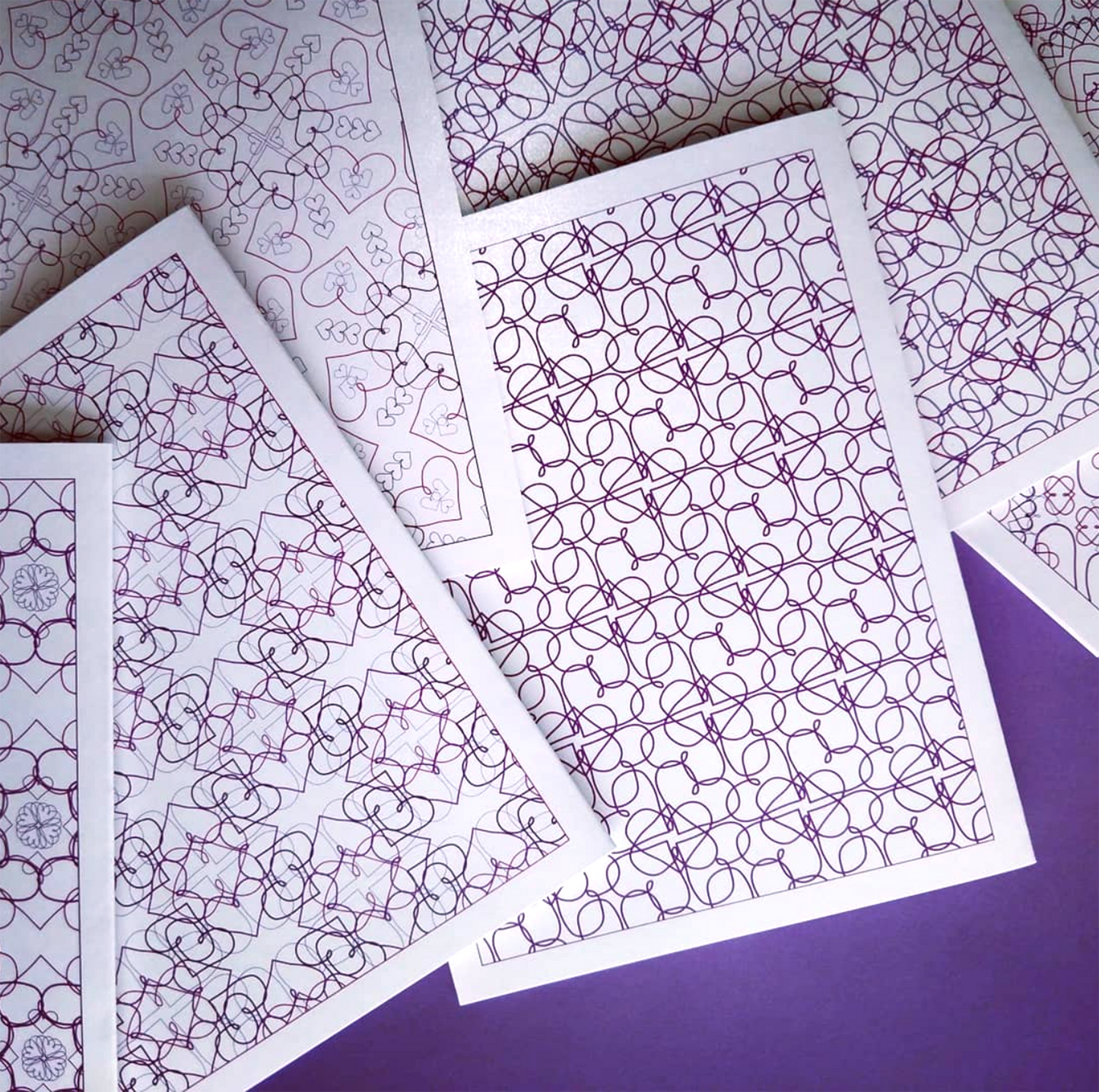 Six overlapping greeting cards on a white background with purple cotton ribbon, beads, and colorful felt balls.