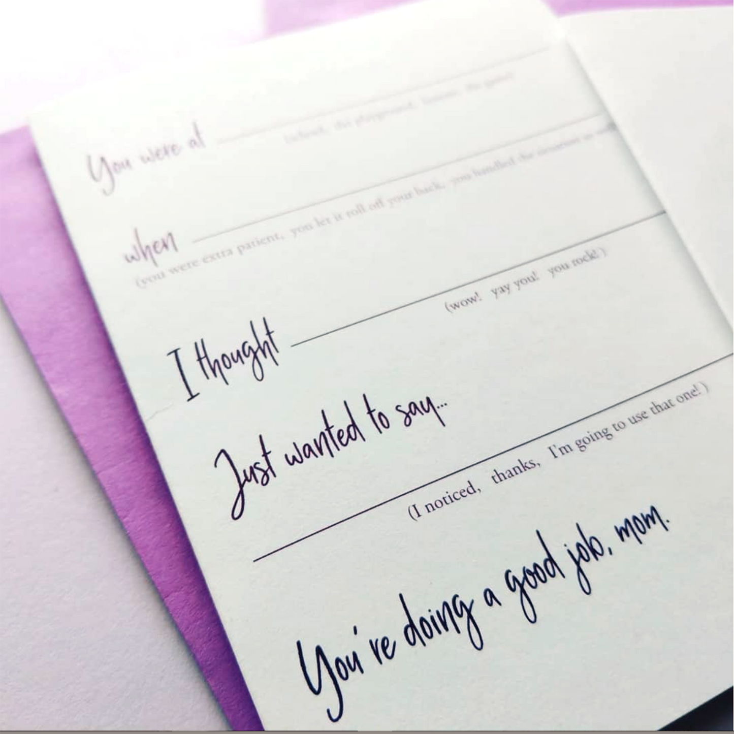 Angled view of greeting card and colored envelope on a white background.