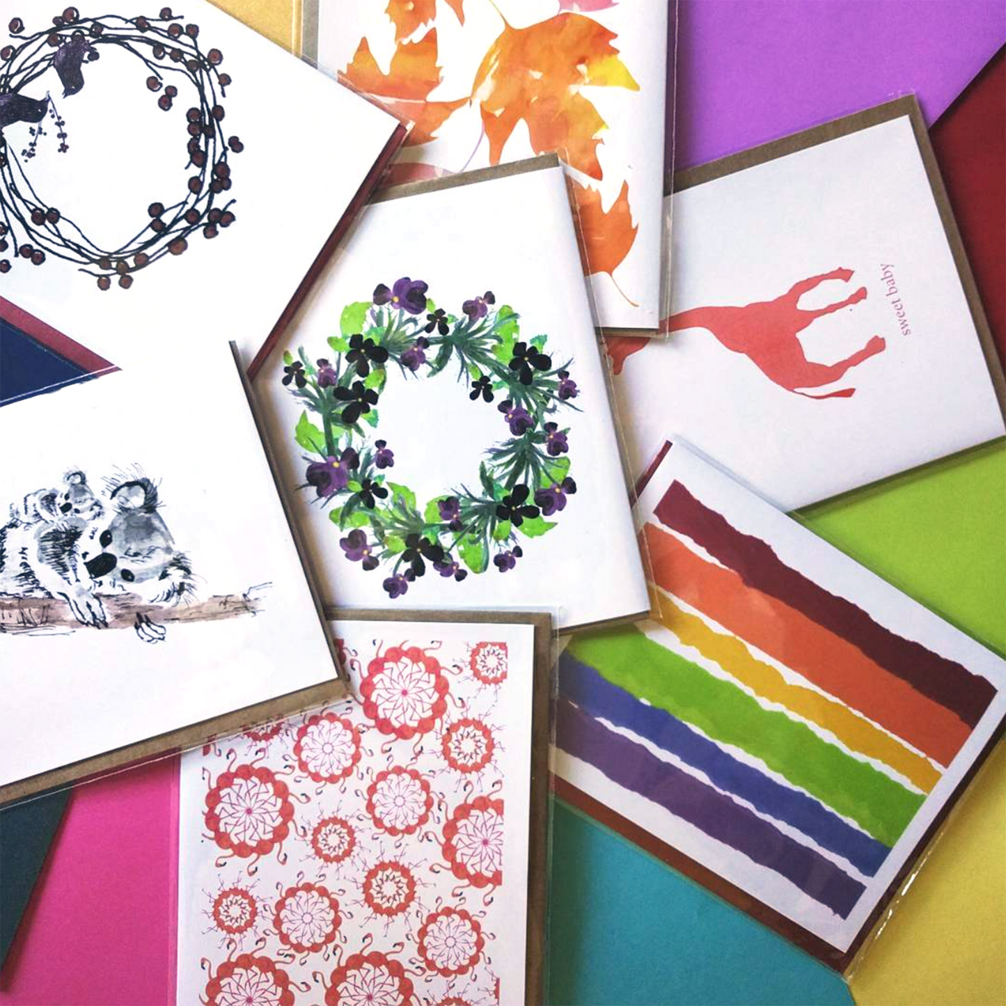 7 overlapping greeting cards layed out on colorful envelopes.