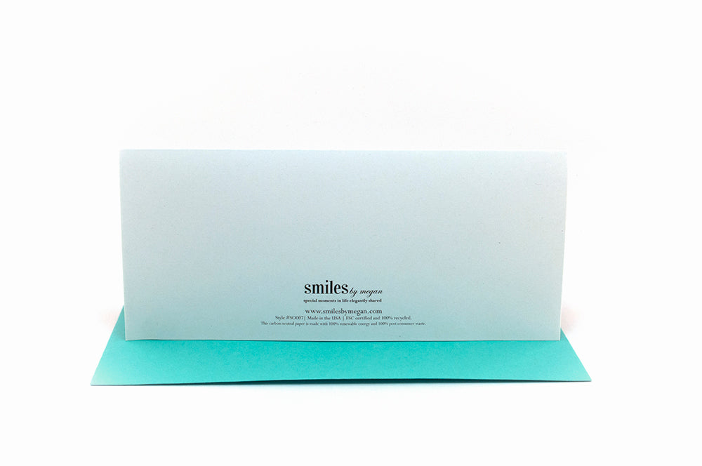Back of greeting card standing upright on top of a colorful envelope against a white background.