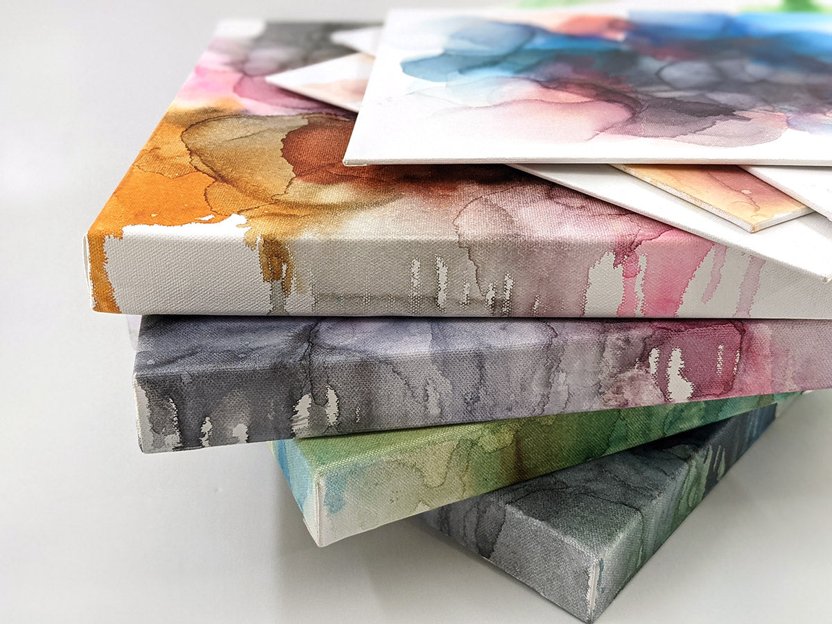Stack of alcohol ink paintings on canvas and panels.