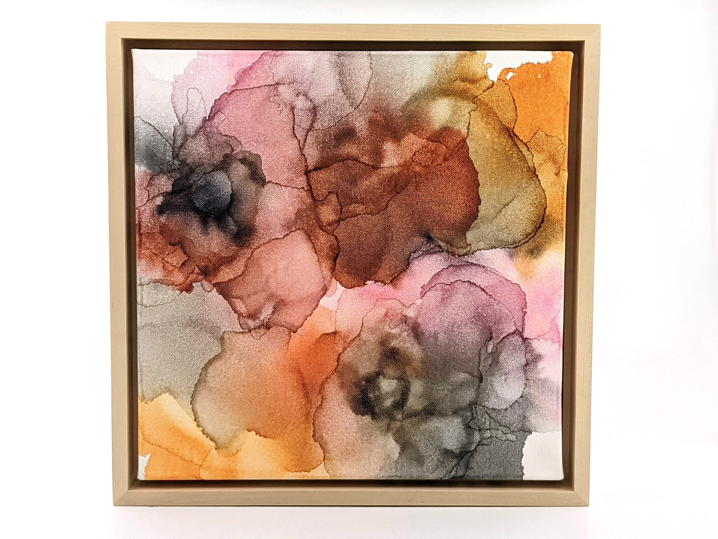 Overhead view of the painting in a light maple float frame.