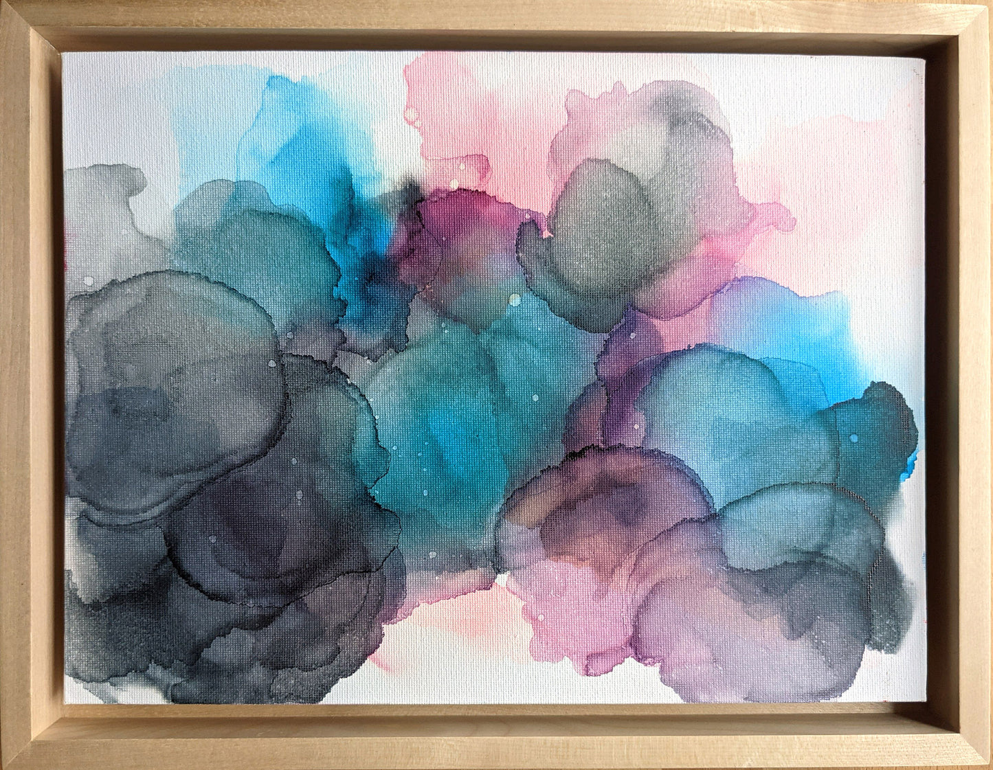 Overhead view of the painting in a light maple float frame.