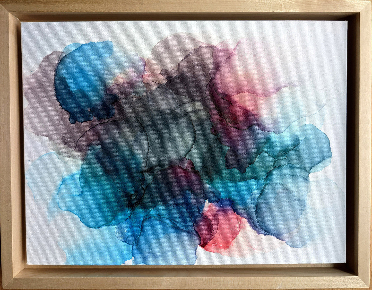 Overhead view of the painting in a light maple float frame.