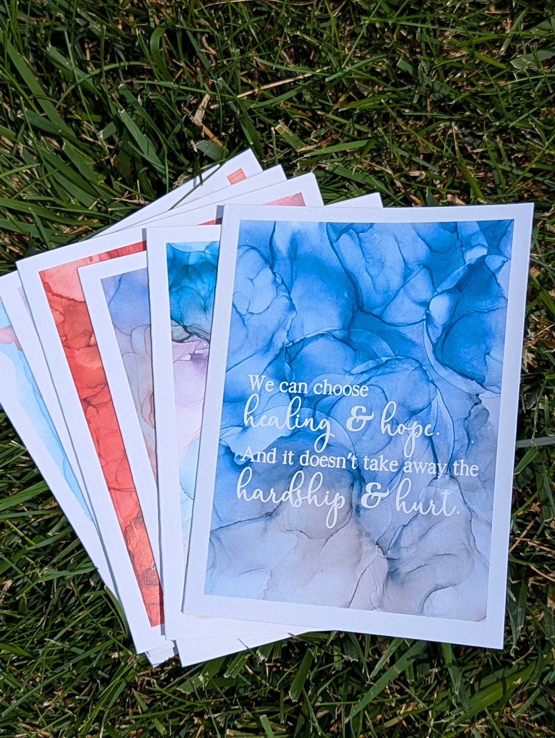Stack of greeting cards with motivational text on a grass background