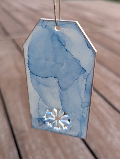 Decorative tag with blue watercolor design and cutout on a wooden surface
