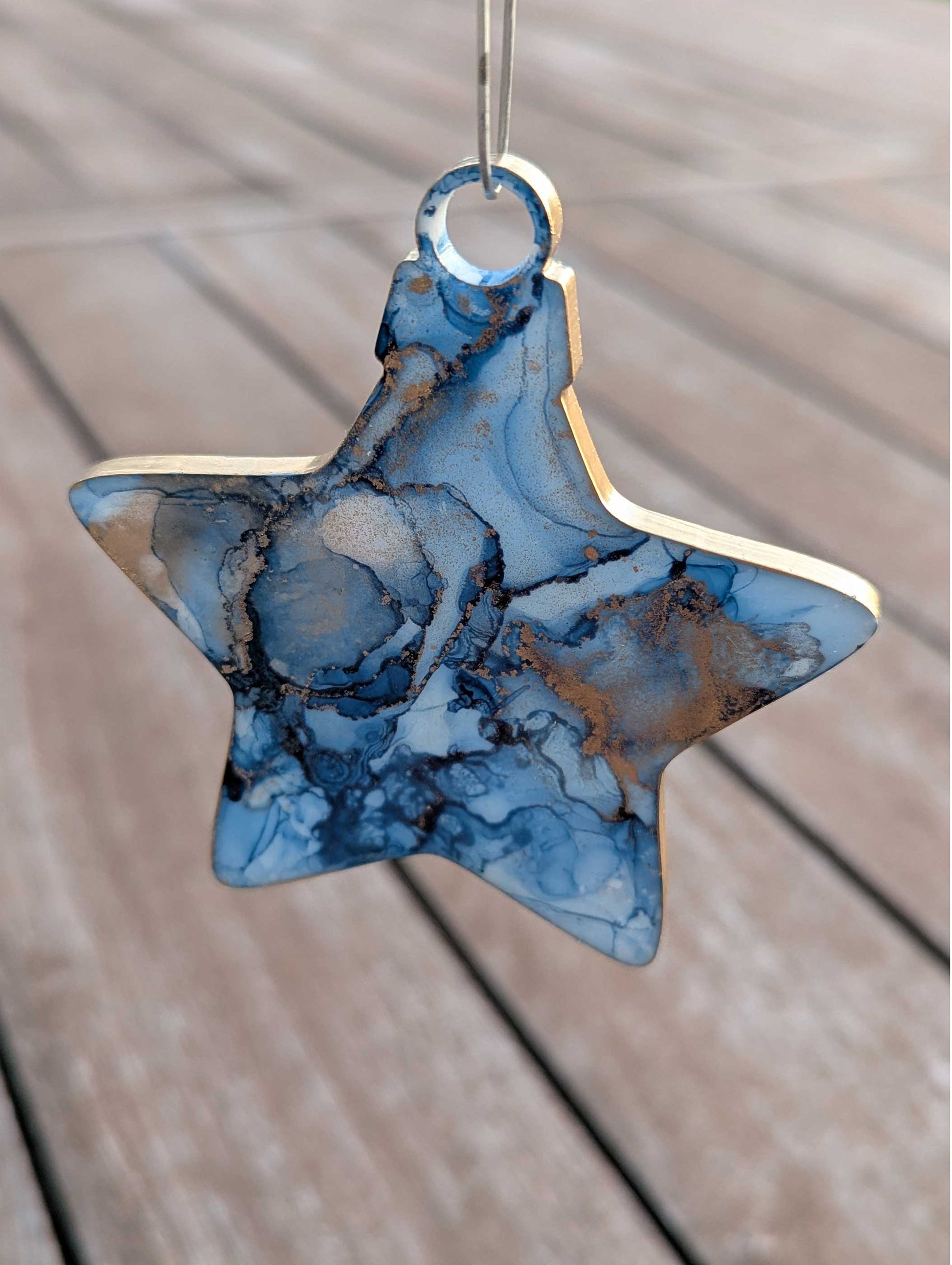 Star-shaped ornament with blue and gray marbled design on a wooden surface