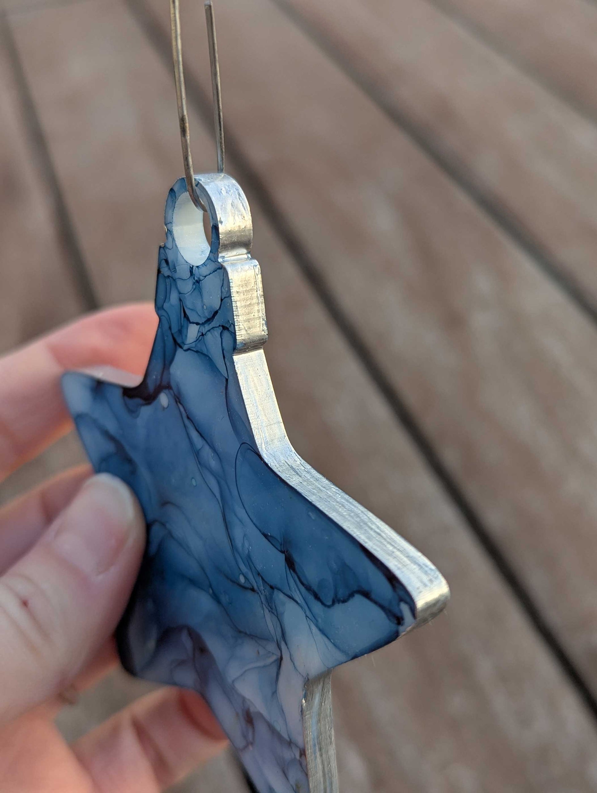 Blue and silver tool held by a hand on a wooden surface