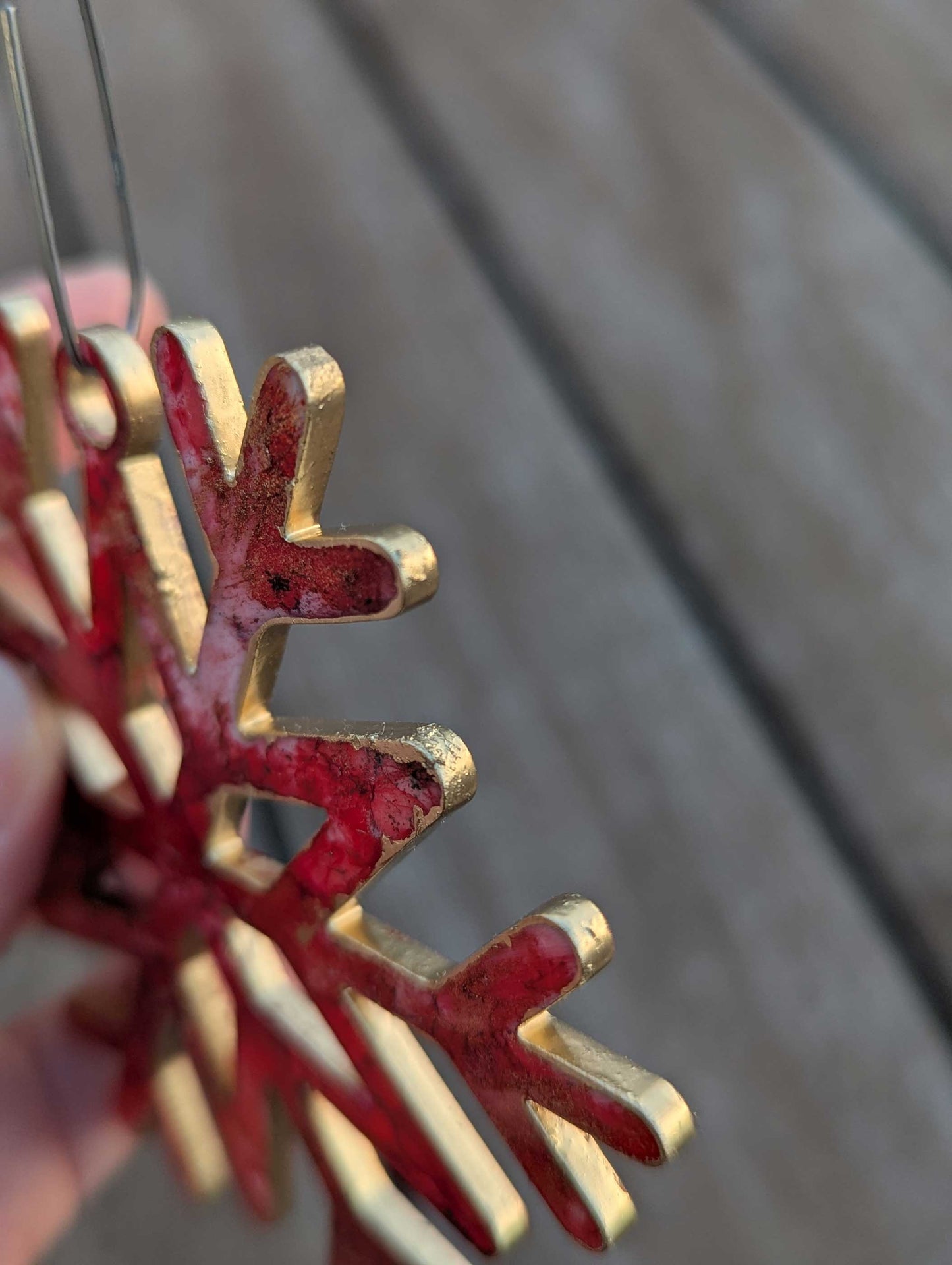 Red and gold snowflake ornament held against a wooden background