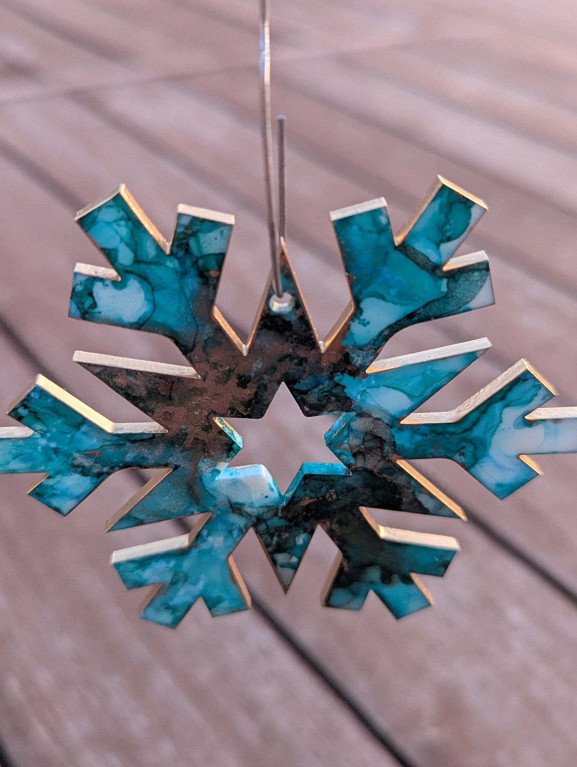 Decorative snowflake ornament with blue and gold design on a wooden surface