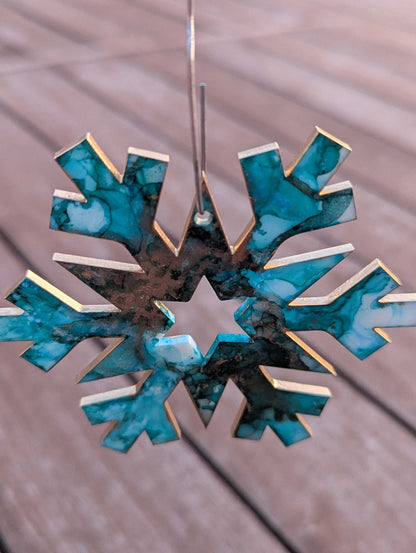 Decorative snowflake ornament with blue and gold design on a wooden surface
