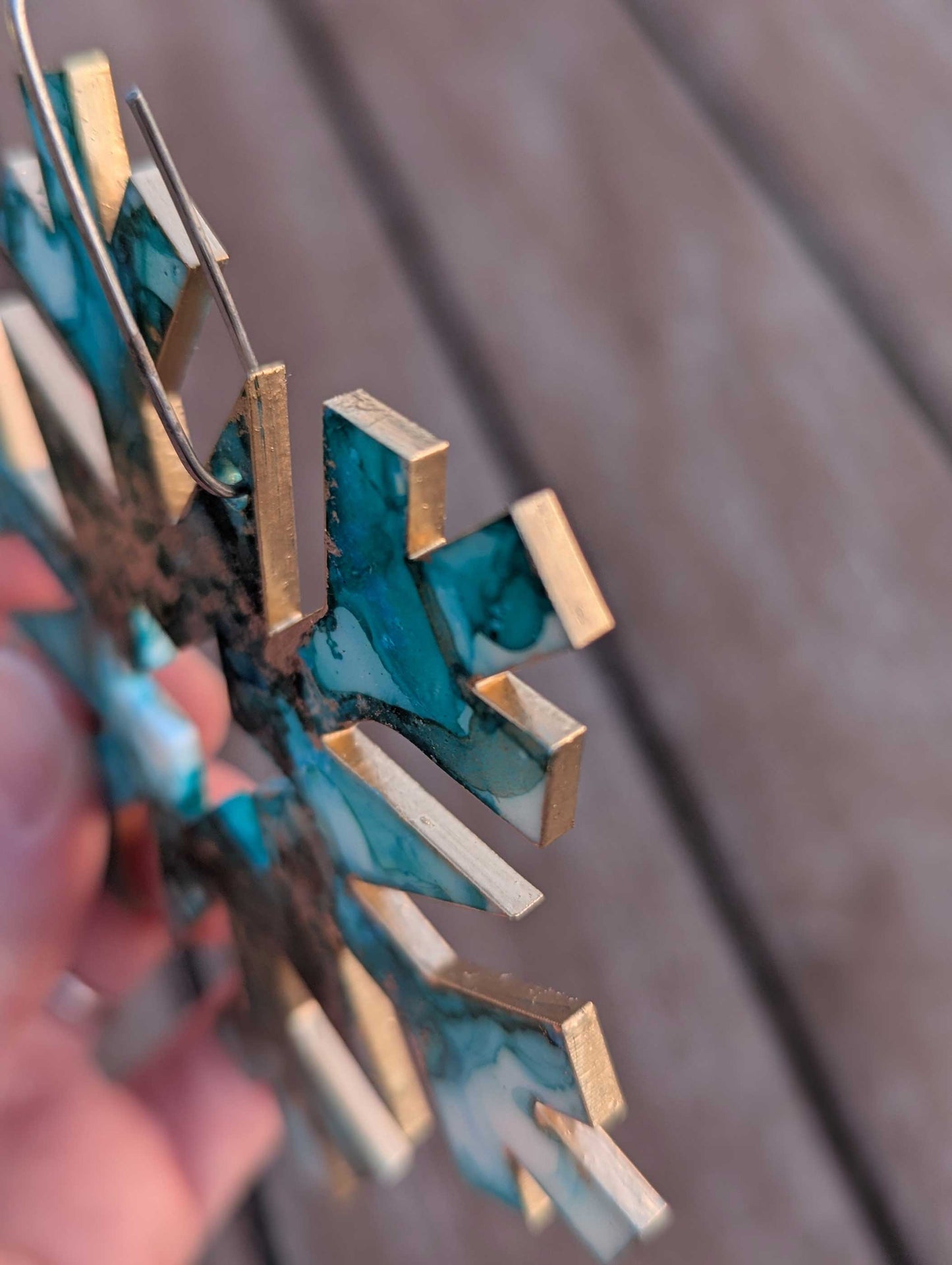 Metallic snowflake ornament held by a hand against a blurred background