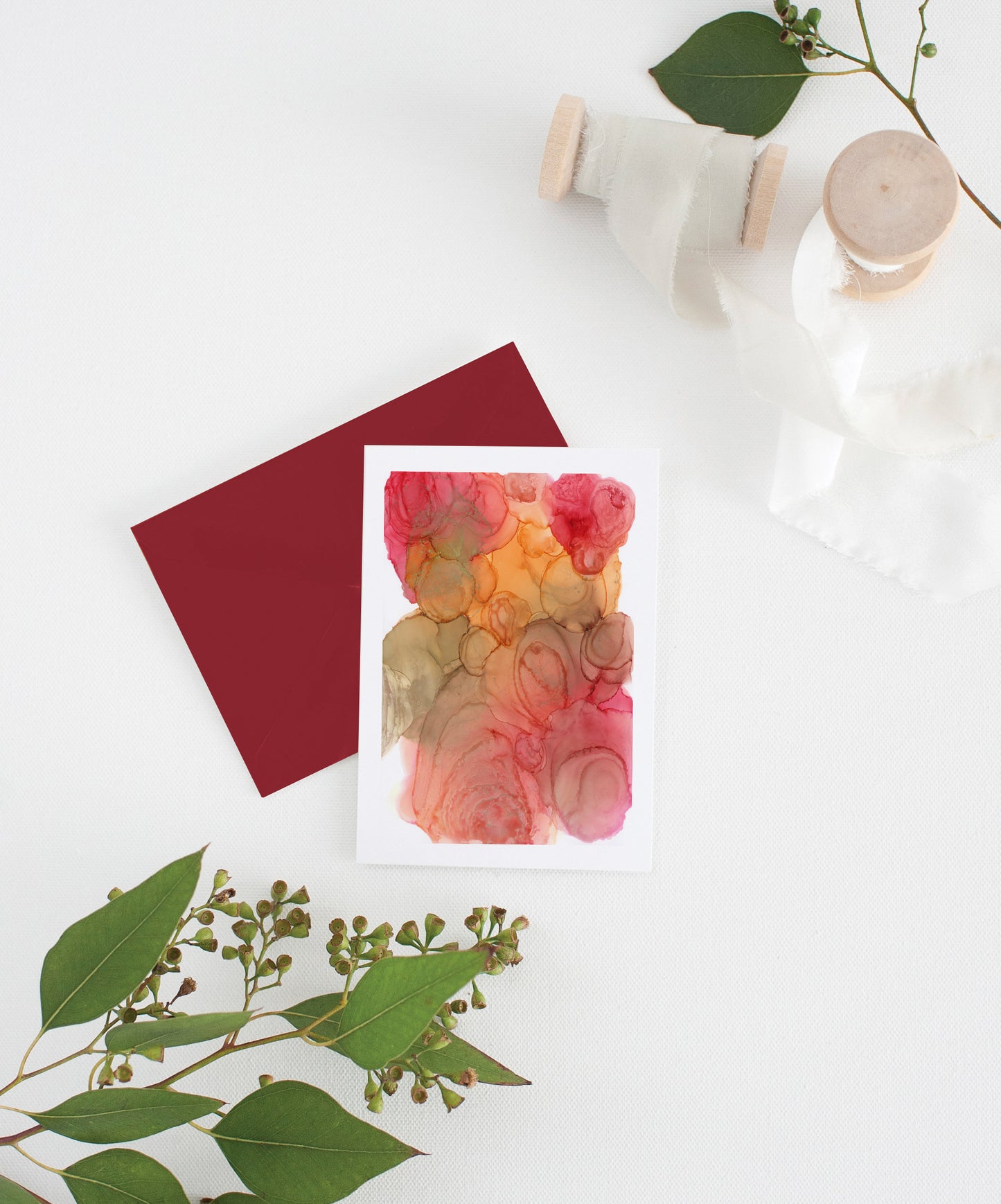 Greeting card, seen from above, with a colored, square flap envelope, pencils, pencil sharpener and shavings on a white background.