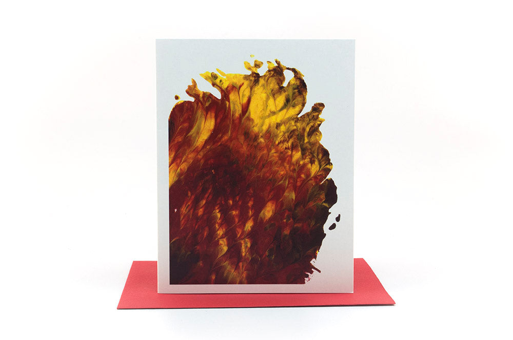 Greeting card showing an abstract painting in reds,  yellows, and browns created from squishing acrylic paint between pieces of cardboard. It sits on a red envelope .