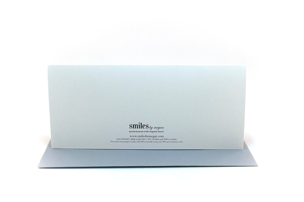 Back of greeting card standing upright on top of a colorful envelope against a white background.