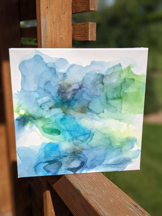 Canvas shown outdoors sitting on a wooden railing with greenery in the background.